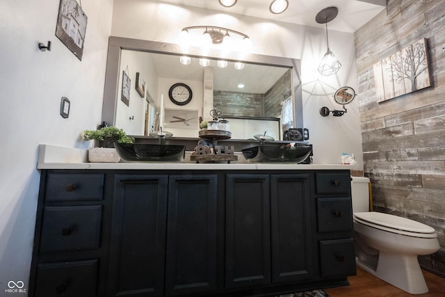 bathroom featuring hardwood / wood-style flooring, vanity, wood walls, and toilet