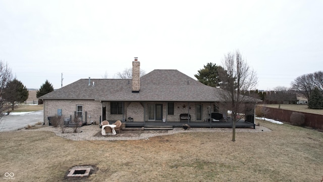 back of house featuring an outdoor fire pit, a deck, and a lawn