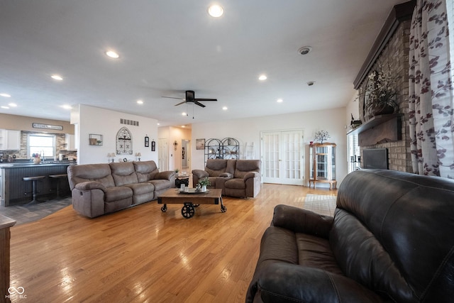 living room with ceiling fan, a fireplace, and light hardwood / wood-style flooring