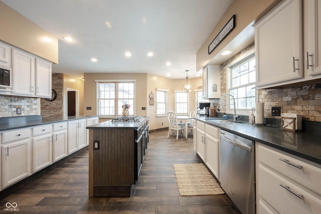 kitchen with stainless steel appliances, sink, white cabinets, and decorative light fixtures