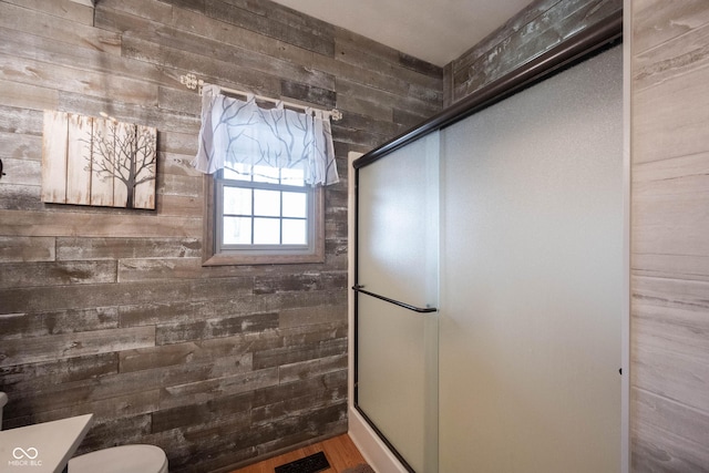 bathroom featuring wooden walls, toilet, and walk in shower