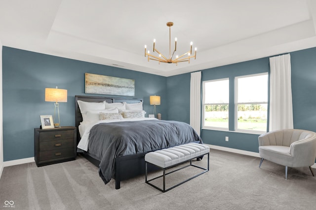 bedroom with light carpet, a notable chandelier, and a tray ceiling