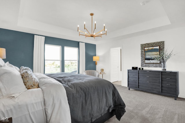 carpeted bedroom featuring an inviting chandelier and a tray ceiling