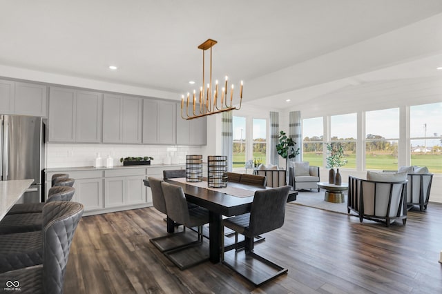 dining room featuring dark wood-type flooring, lofted ceiling, and a chandelier