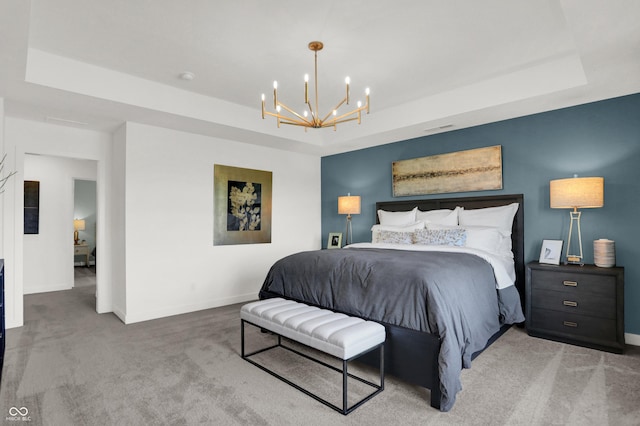 carpeted bedroom featuring a chandelier and a tray ceiling