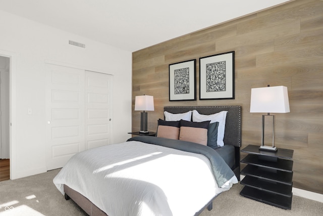 carpeted bedroom with wooden walls and a closet