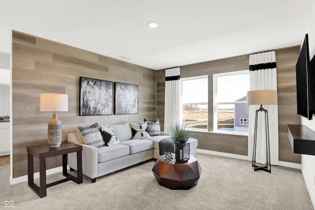 carpeted living room featuring wood walls