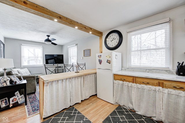 kitchen featuring beamed ceiling, plenty of natural light, white fridge, and light hardwood / wood-style flooring