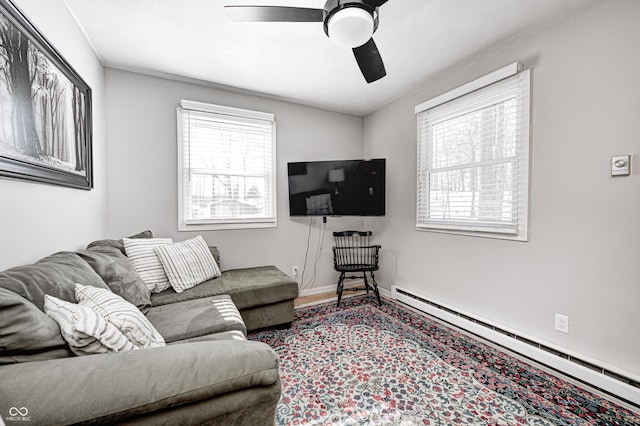 living room featuring baseboard heating, ceiling fan, a healthy amount of sunlight, and wood-type flooring