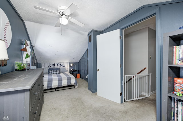 carpeted bedroom with ceiling fan, vaulted ceiling, and a textured ceiling