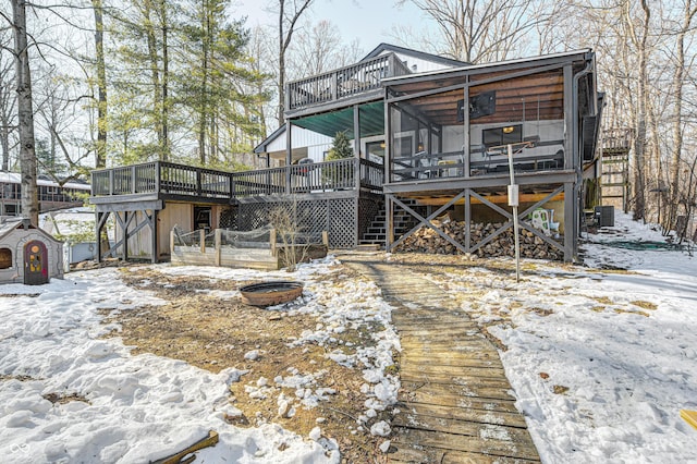 snow covered back of property with a deck