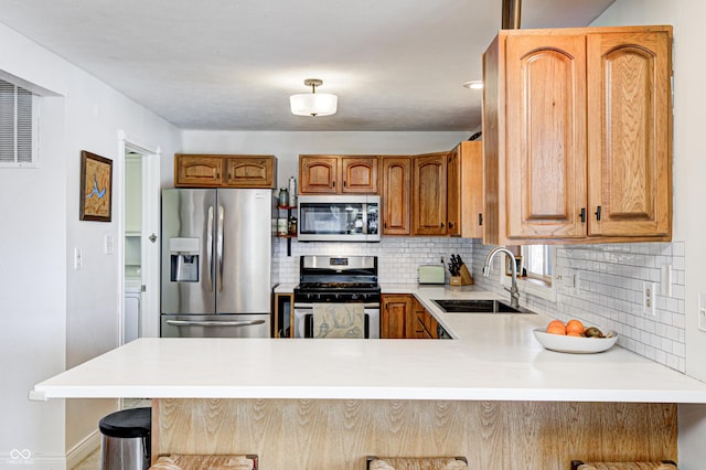 kitchen featuring sink, a kitchen breakfast bar, stainless steel appliances, and kitchen peninsula