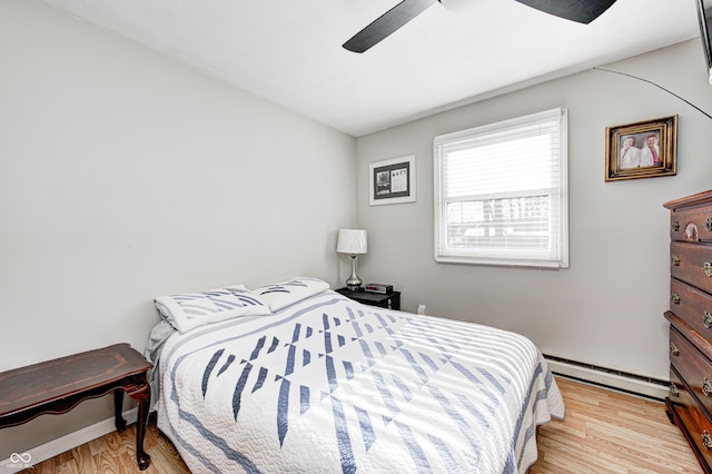 bedroom featuring ceiling fan, light wood-type flooring, and a baseboard heating unit