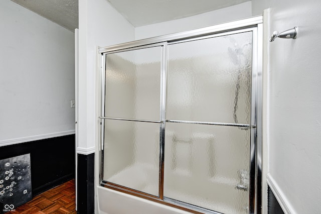 bathroom featuring bath / shower combo with glass door and parquet flooring