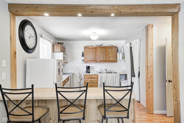 kitchen with butcher block counters, sink, white appliances, and light hardwood / wood-style floors