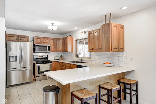 kitchen with sink, light tile patterned floors, a kitchen breakfast bar, kitchen peninsula, and stainless steel appliances