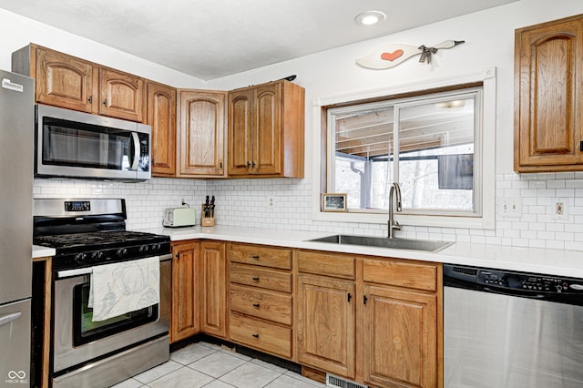 kitchen featuring backsplash, stainless steel appliances, sink, and light tile patterned floors