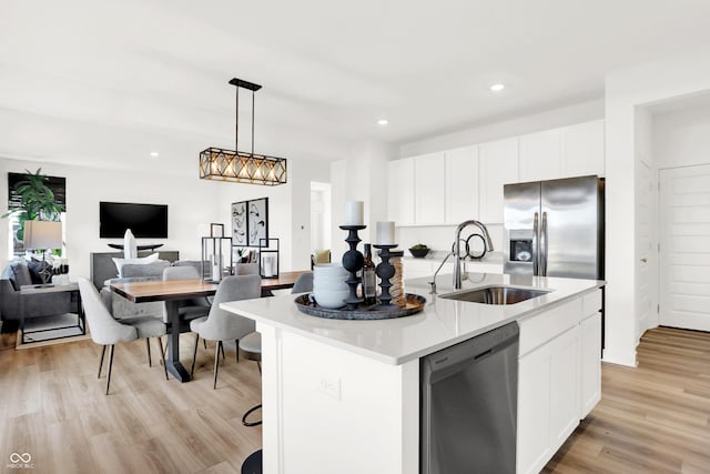 kitchen with appliances with stainless steel finishes, a kitchen island with sink, sink, and white cabinets