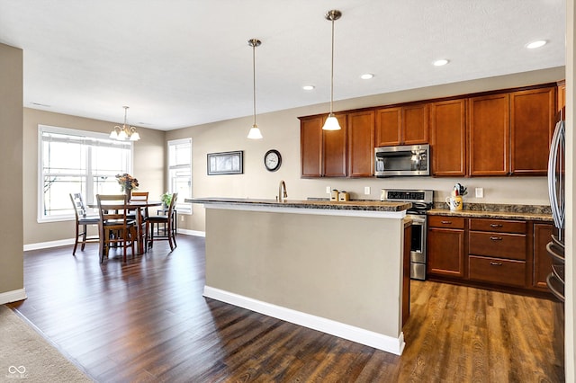 kitchen featuring stainless steel appliances, a kitchen island with sink, dark hardwood / wood-style floors, and decorative light fixtures