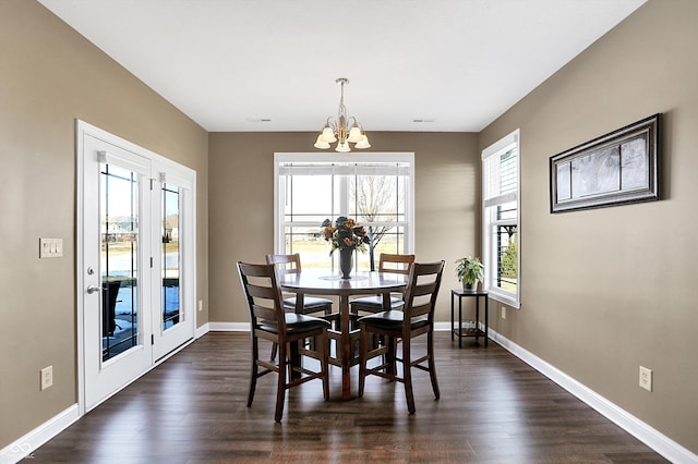 dining space with dark hardwood / wood-style flooring and a chandelier