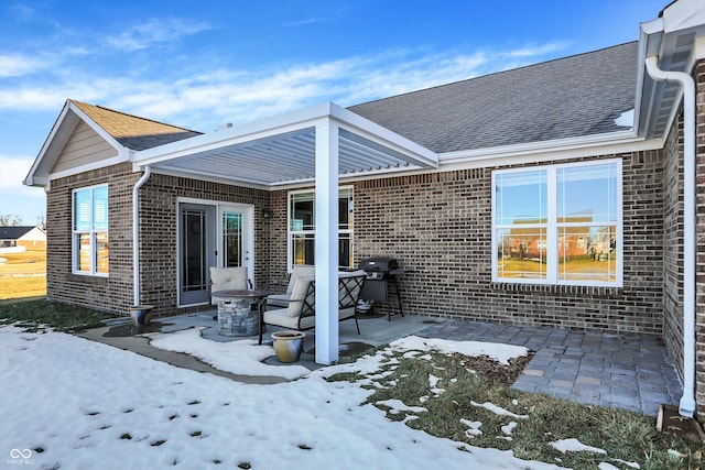 snow covered rear of property with an outdoor fire pit and a patio