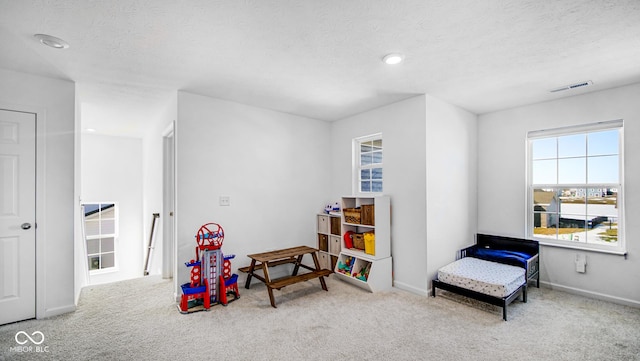 playroom with light carpet and a textured ceiling