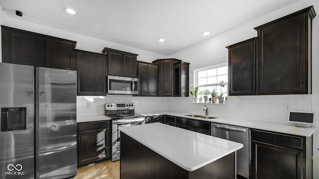 kitchen with appliances with stainless steel finishes, sink, decorative backsplash, a center island, and light wood-type flooring