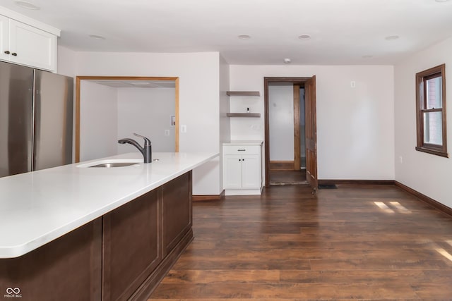 kitchen featuring sink, dark wood-type flooring, stainless steel refrigerator, an island with sink, and white cabinets