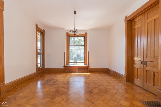 spare room with an inviting chandelier and light parquet floors