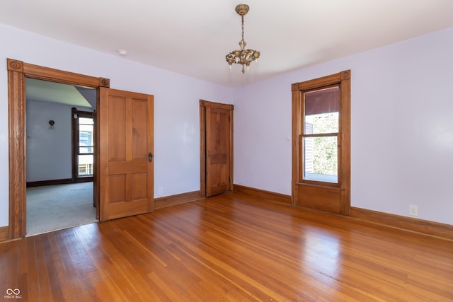 spare room featuring hardwood / wood-style flooring and a notable chandelier