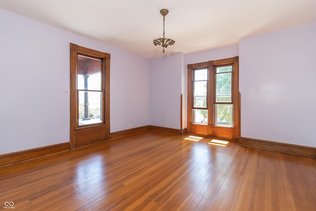 spare room with an inviting chandelier, hardwood / wood-style floors, and a wealth of natural light