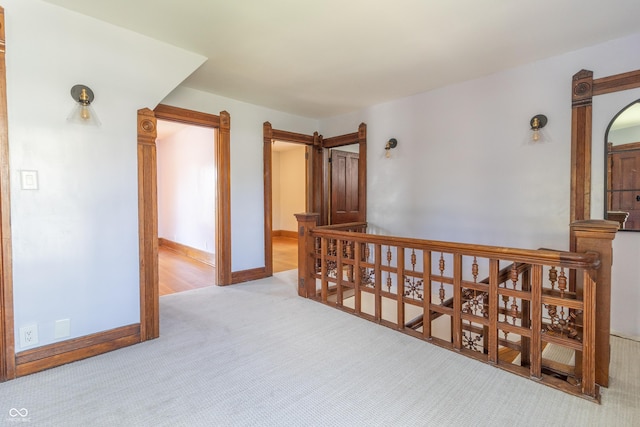 corridor featuring a barn door and light carpet