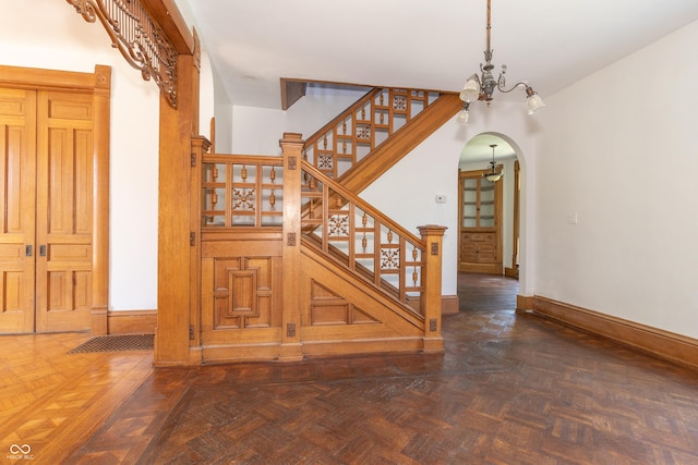 stairway featuring parquet floors and an inviting chandelier