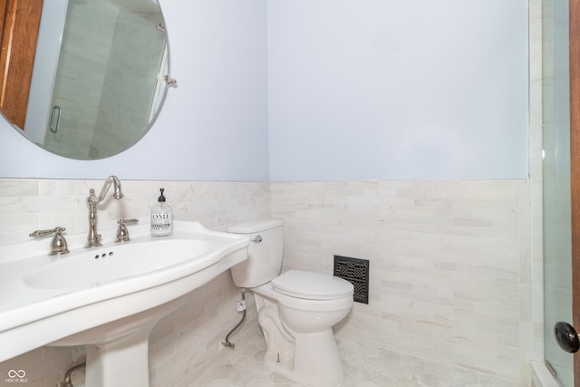 bathroom featuring tile patterned flooring, a shower with shower door, toilet, and tile walls