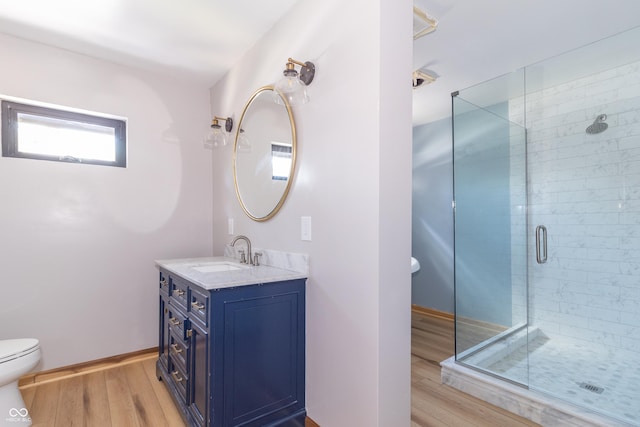 bathroom with hardwood / wood-style flooring, vanity, a shower with door, and toilet