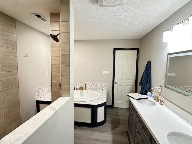 bathroom featuring vanity, a textured ceiling, wood-type flooring, and a washtub