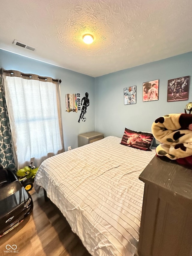 bedroom featuring wood-type flooring and a textured ceiling