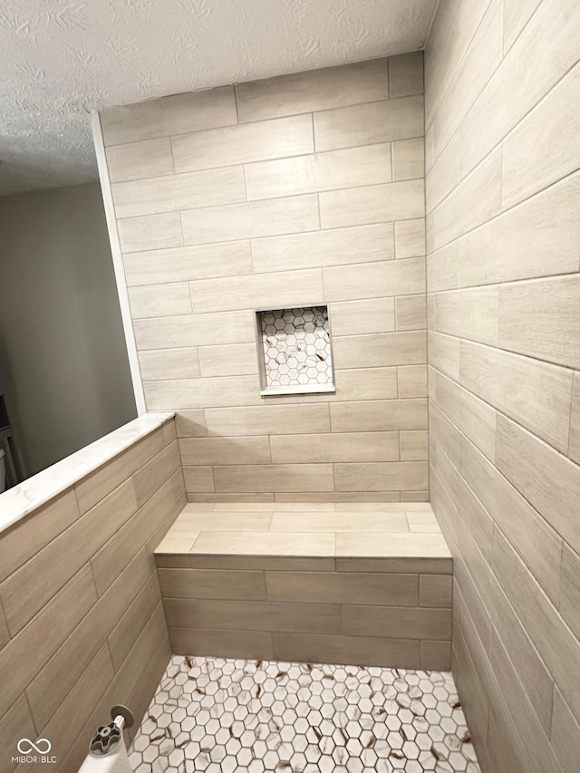 bathroom featuring a textured ceiling and tiled shower