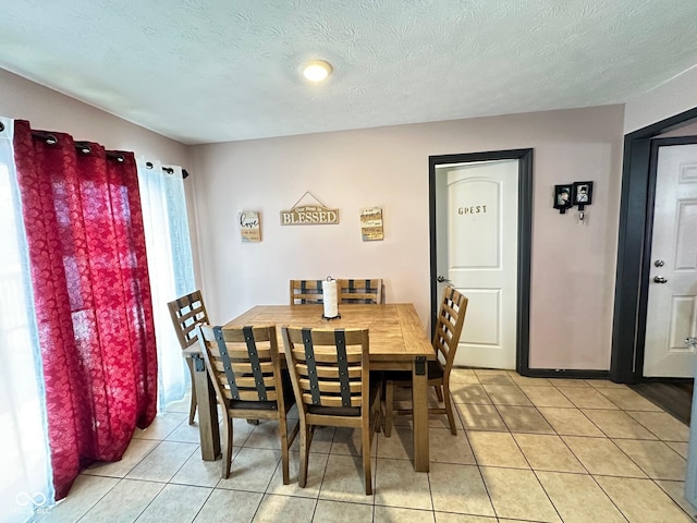 dining space with a textured ceiling and light tile patterned floors