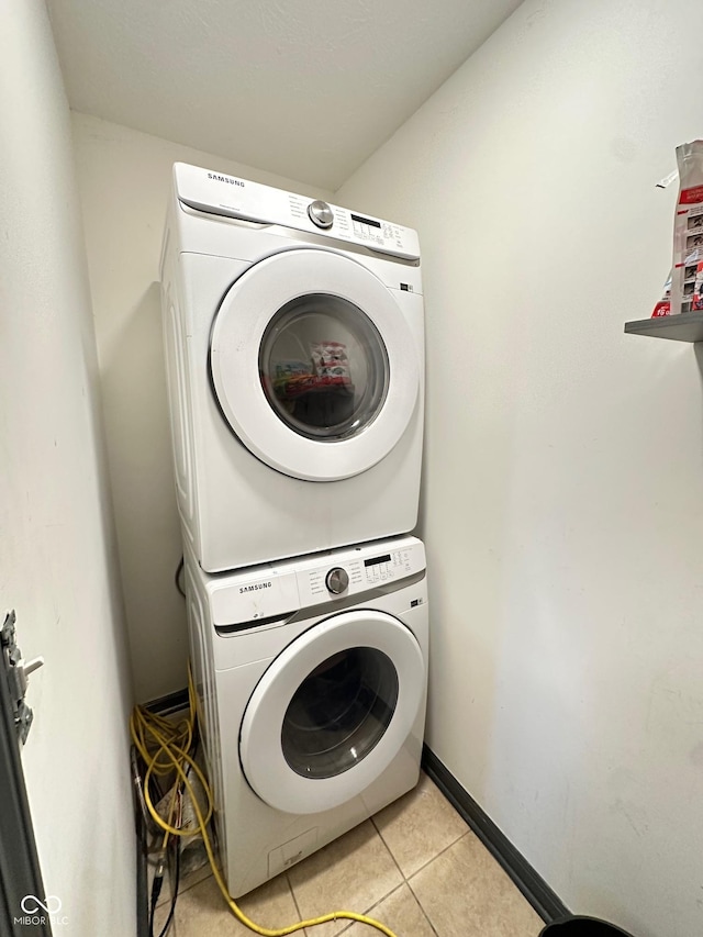 laundry area featuring stacked washer and clothes dryer and light tile patterned floors