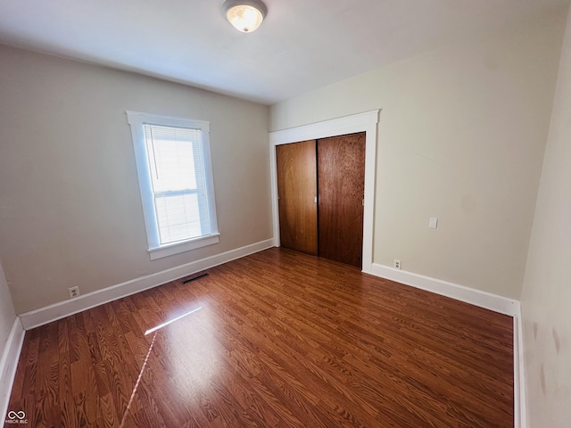 unfurnished bedroom featuring a closet and dark hardwood / wood-style floors