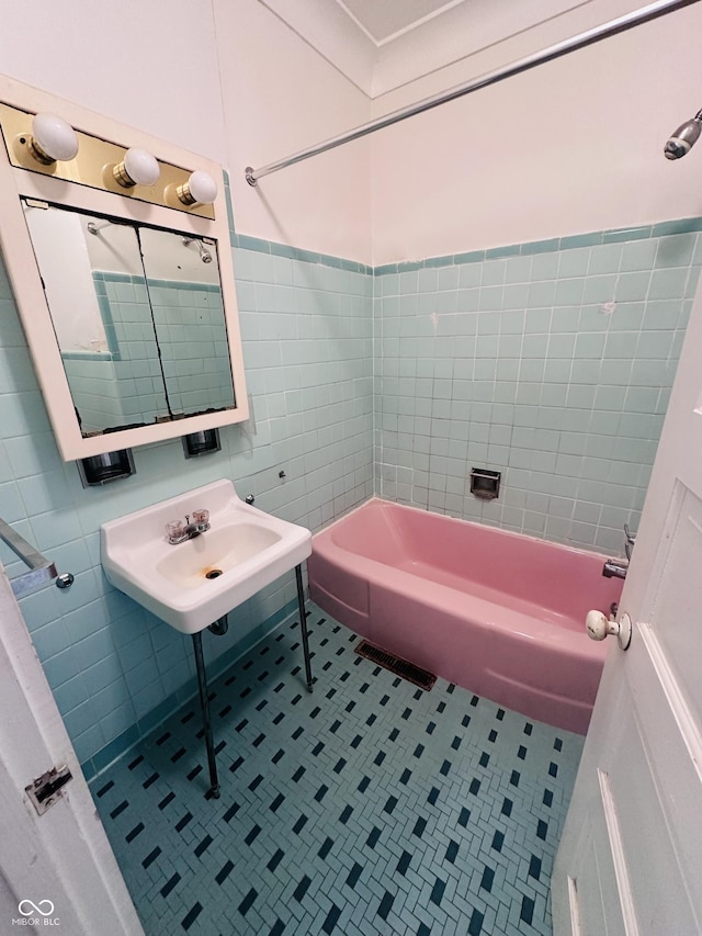 bathroom with shower / bathing tub combination, sink, tile patterned flooring, and tile walls