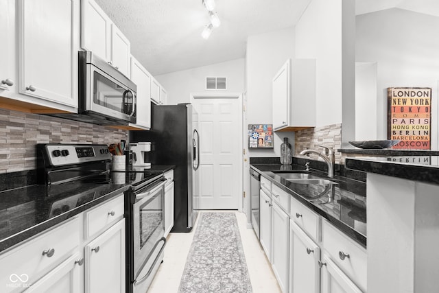 kitchen featuring white cabinetry, appliances with stainless steel finishes, vaulted ceiling, and sink