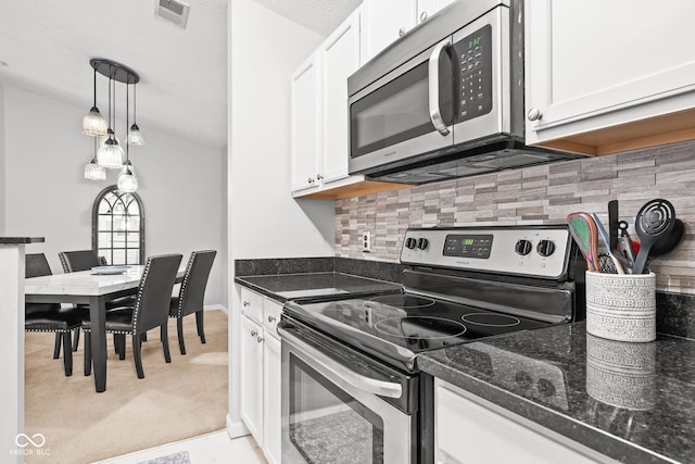 kitchen with stainless steel appliances, pendant lighting, white cabinets, and backsplash