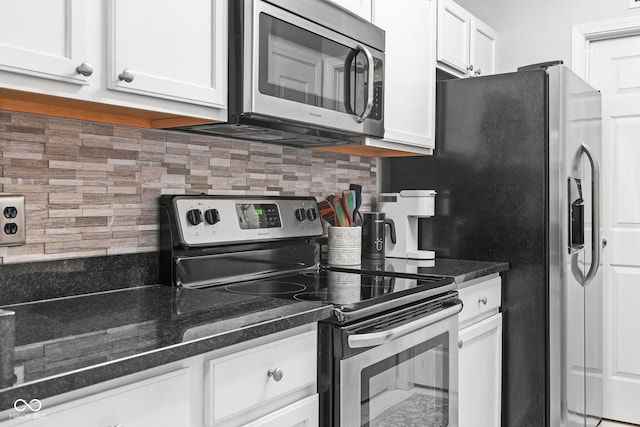 kitchen featuring stainless steel appliances, white cabinetry, backsplash, and dark stone counters