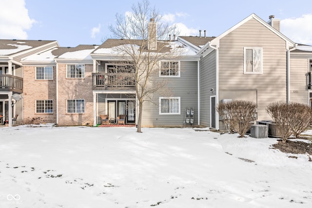 snow covered rear of property featuring a balcony