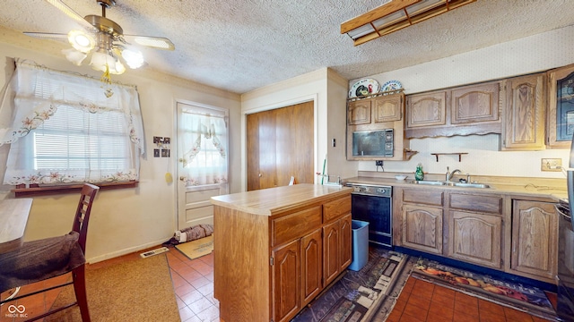 kitchen featuring sink, a textured ceiling, black dishwasher, dark tile patterned floors, and ceiling fan