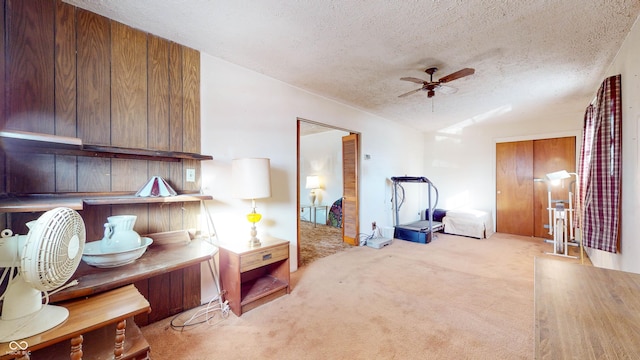 sitting room with light carpet, ceiling fan, and a textured ceiling