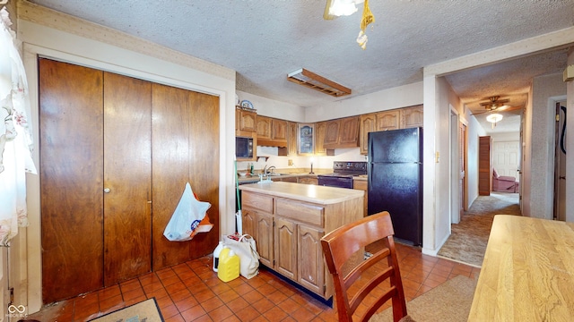 kitchen with sink, dark tile patterned floors, black appliances, and a textured ceiling