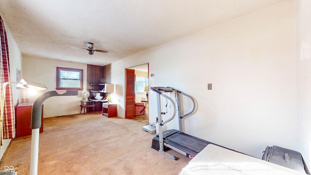 workout area featuring a healthy amount of sunlight, light colored carpet, a textured ceiling, and ceiling fan